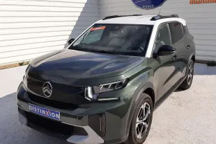 Vue 3/4 avant droite d'un Citroën C3 Aircross 2025 vert Montana avec toit blanc et jantes biton, stationné devant un mur blanc.