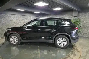 Vue de profil côté gauche d’un Volkswagen Tiguan noir 2025 avec jantes alliage 17 pouces dans un showroom.
