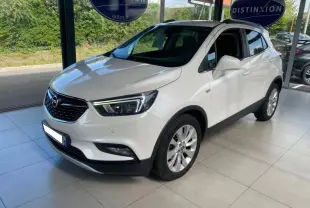 Opel Mokka blanc en 3/4 avant droit, avec jantes alliage et calandre noire brillante dans un showroom lumineux.