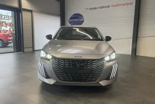 Vue frontale d'une Peugeot 208 1.2i Hybrid gris Artense avec phares LED et calandre noire brillante en showroom.