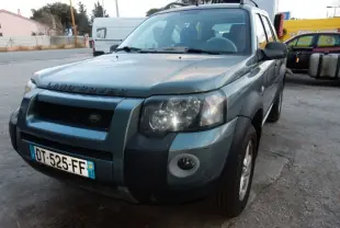 Vue 3/4 avant gauche d'un Land Rover Freelander gris 2004 avec calandre noire et plaques françaises visibles.