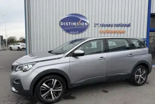 Peugeot 5008 gris Artense vue de profil côté gauche, stationnée devant un bâtiment avec enseigne Distinxion.