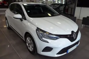 Renault Clio V blanche Glacier vue 3/4 avant droit en showroom, avec phares LED et calandre noire brillante.