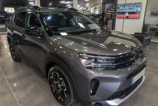 Vue 3/4 avant droite d'un Citroën C5 Aircross Hybride gris Platinium avec jantes noires biton dans un showroom.