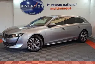 Peugeot 508 break gris clair en 3/4 avant droit, avec jantes alliage et feux LED, stationné en intérieur showroom.