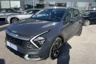 KIA Sportage gris Eclipse Metal en 3/4 avant droit, avec calandre noire et feux LED distinctifs, stationné en extérieur.