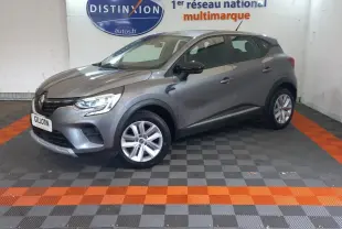Renault Captur Business TCe 100 gris clair vu de profil côté gauche dans un showroom avec sol gris et orange.