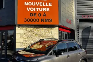 Citroën C3 Aircross gris foncé vue 3/4 avant droit, avec barres de toit noires et jantes alliage distinctives.