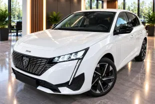 Peugeot 308 blanc okenite vue 3/4 avant droit, calandre noire distinctive et jantes alliage bicolores.