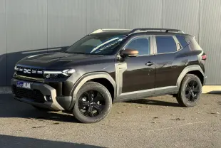 Dacia Duster 2026 noir nacré en 3/4 avant droit avec jantes noires et coques de rétroviseur brun cuivré.