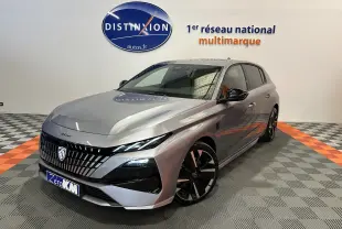 Peugeot 308 gris Artense vue 3/4 avant droit en showroom avec jantes noires et logo Distinxion en arrière-plan.