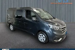 Renault Trafic Fourgon gris en 3/4 avant droit, vitres surteintées et jantes argentées visibles sur fond neutre.