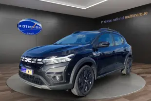 Dacia Sandero Stepway noir en 3/4 avant droit, avec barres de toit et jantes noires distinctives.