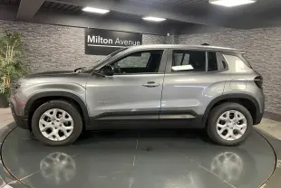 Profil côté gauche du Jeep Avenger gris métallisé 2024 avec jantes alliage et coques de rétroviseurs noires.