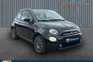 Vue 3/4 avant d'une FIAT 500C noire 2024 avec jantes alliage et roue de secours visible sur le côté droit.