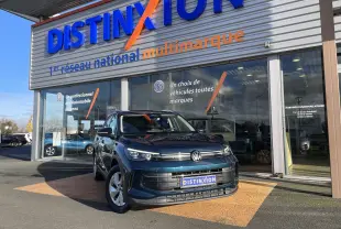Volkswagen Tiguan 2.0 TDI 150 DSG Life Plus en Nightshade Blue, vue 3/4 avant devant un showroom Distinxion.