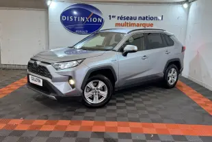Toyota RAV4 hybride gris clair en 3/4 avant droit, avec phares allumés et jantes alliage visibles