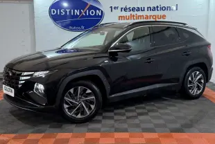 Vue 3/4 avant gauche d'un Hyundai Tucson noir brillant avec jantes alliage et vitres teintées en intérieur showroom.