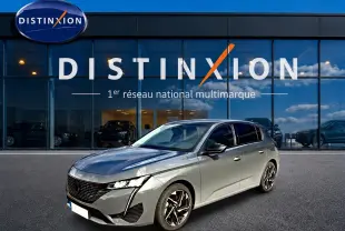 Peugeot 308 gris selenium vue 3/4 avant droit, avec jantes alliage et calandre noire distinctive.