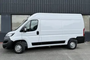 Vue de profil côté gauche d’un Peugeot Boxer Fourgon blanc avec protections noires et jantes acier.