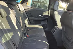 DS7 gris Artens en 3/4 avant droit, avec calandre noire distinctive et jantes noires brillantes, devant un showroom Distinxion.