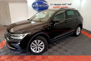Volkswagen Tiguan noir vu en 3/4 avant droit dans un showroom avec jantes argentées et toit noir.