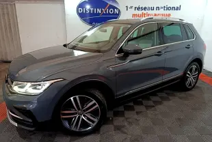 Volkswagen Tiguan gris clair vu en 3/4 avant droit, avec phares LED allumés et jantes alliage distinctives.