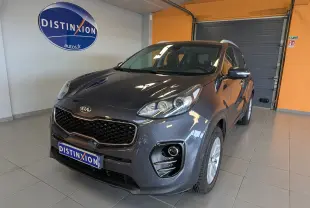 KIA Sportage gris en 3/4 avant droit dans un showroom avec calandre noire et jantes argentées.