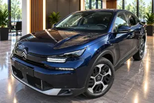 Citroën C4 1,2 Hybrid 2025 bleu eclipse vue 3/4 avant en intérieur avec jantes distinctives et éclairage LED.
