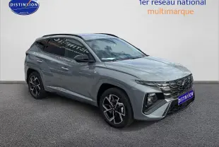 Vue 3/4 avant du Hyundai Tucson 2026 gris Shadow avec calandre noire brillante et jantes alliage 19 pouces.