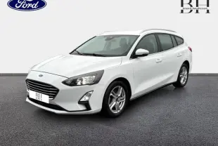 Ford Focus SW blanc glacier vue 3/4 avant droit avec jantes alu et barres de toit visibles.
