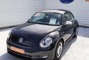 Volkswagen New Beetle noir en 3/4 avant droit, avec jantes spécifiques et rétroviseurs chromés visibles.