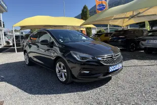 Opel Astra noire 2016 vue 3/4 avant droit sur parking avec panneau "OCCASION" à l'avant.