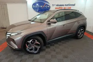Vue 3/4 avant droite d'un Hyundai Tucson marron 2022 hybride rechargeable dans un showroom intérieur.