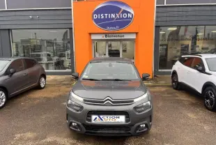 Vue avant d'une Citroën C4 Cactus gris Platinium, avec calandre distinctive et phares LED, devant un garage orange.