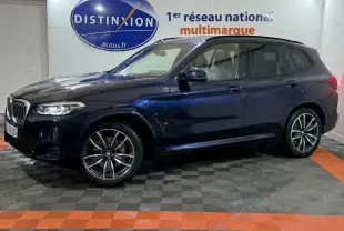 BMW X3 xDrive30e bleu en vue de profil côté gauche dans un showroom avec éclairage intérieur et logo Distinxion en arrière-plan