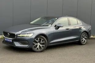 Volvo S60 gris Denim vue 3/4 avant droit, avec jantes alliage 17 pouces et contours de fenêtres chromés.