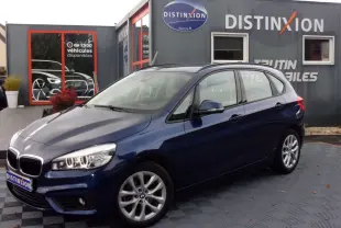 BMW Série 2 Active Tourer bleu nuit vue 3/4 avant droit, avec phares allumés et jantes alliage multibranches.