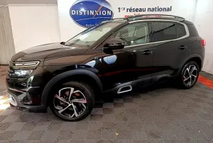 Vue de profil côté gauche d'un Citroën C5 Aircross Hybrid noir avec jantes alliage et barres de toit chromées.