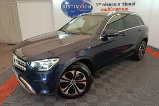 Mercedes GLC hybride rechargeable bleu en 3/4 avant droit, avec jantes alliage et phares LED allumés.