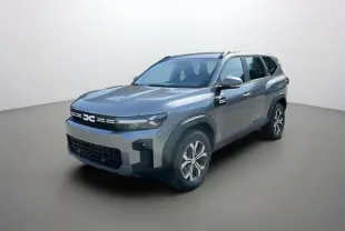 SUV Dacia Bigster gris schiste en 3/4 avant droit avec jantes alu et barres de toit visibles.