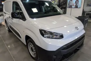 Toyota Proace City Long blanc glacier vue 3/4 avant droit en intérieur avec détails noirs contrastants sur pare-chocs et rétroviseurs.