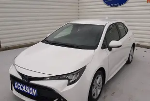 Vue 3/4 avant d'une Toyota Corolla blanche hybride 2022 avec calandre noire et plaque "OCCASION" visible.
