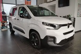 Citroën Berlingo blanc vue 3/4 avant droit en intérieur, avec jantes alu noir Starlit et rails latéraux couleur carrosserie.