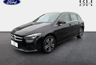 Mercedes Classe B 250 e noire cosmos métallisé vue 3/4 avant avec jantes alliage et phares LED allumés.