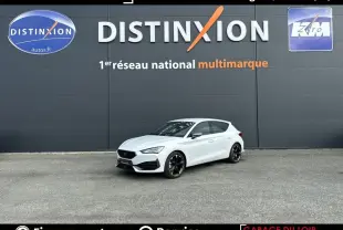Vue 3/4 avant droite d'une CUPRA Leon 1.4 e-Hybrid blanche, avec jantes noires et calandre distinctive noire.