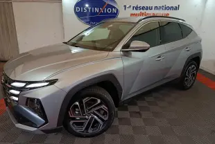 Vue 3/4 avant droit d'un Hyundai Tucson gris clair 2025 avec jantes alliage et calandre distinctive.