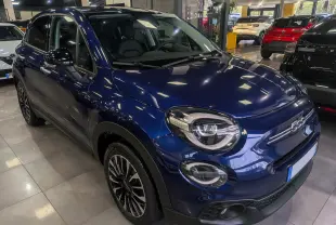 Vue 3/4 avant gauche d'une FIAT 500X 2024 bleu Venezia avec jantes noires et phares LED en showroom.