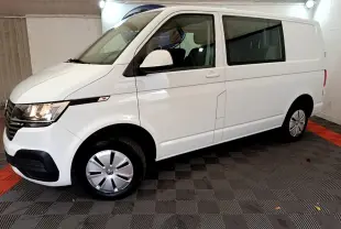 Vue de profil côté gauche d'un Volkswagen Transporter blanc 2.0 TDi 150 DSG7 Business avec vitres arrière teintées.