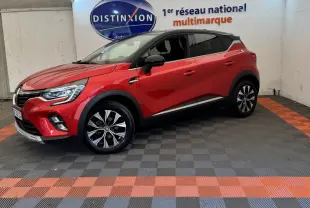 Renault Captur rouge en 3/4 avant droit, toit noir, jantes alliage et feux LED visibles en intérieur showroom.